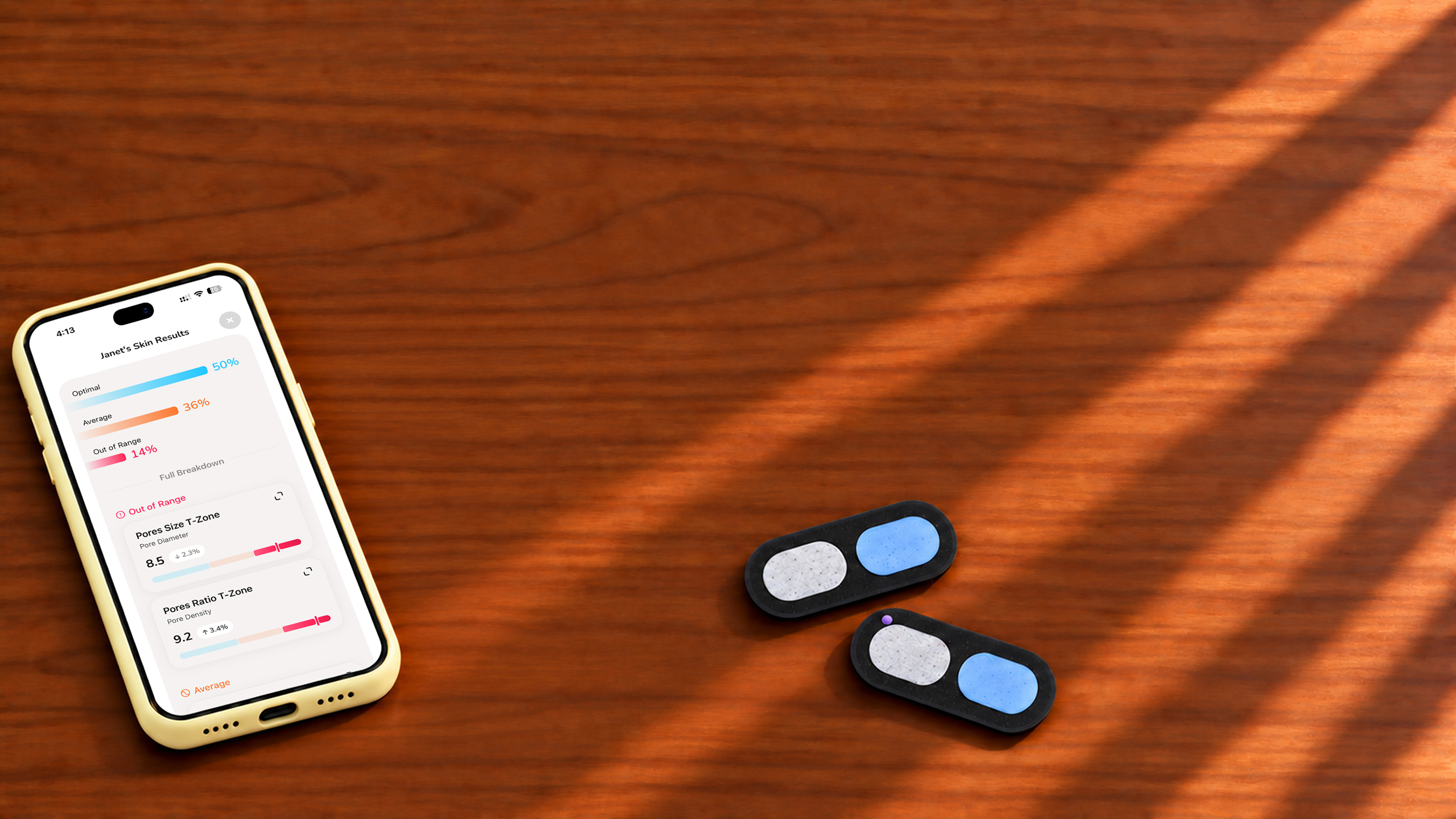 Two used Skinfield Analyzers beside a phone showing skin analysis results, on a wooden table